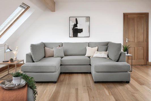 Gray sectional sofa in a modern living room with wooden floor and white walls.