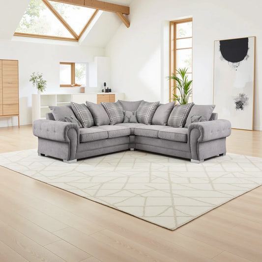 Gray sectional sofa in a modern living room with large windows and light wood flooring.