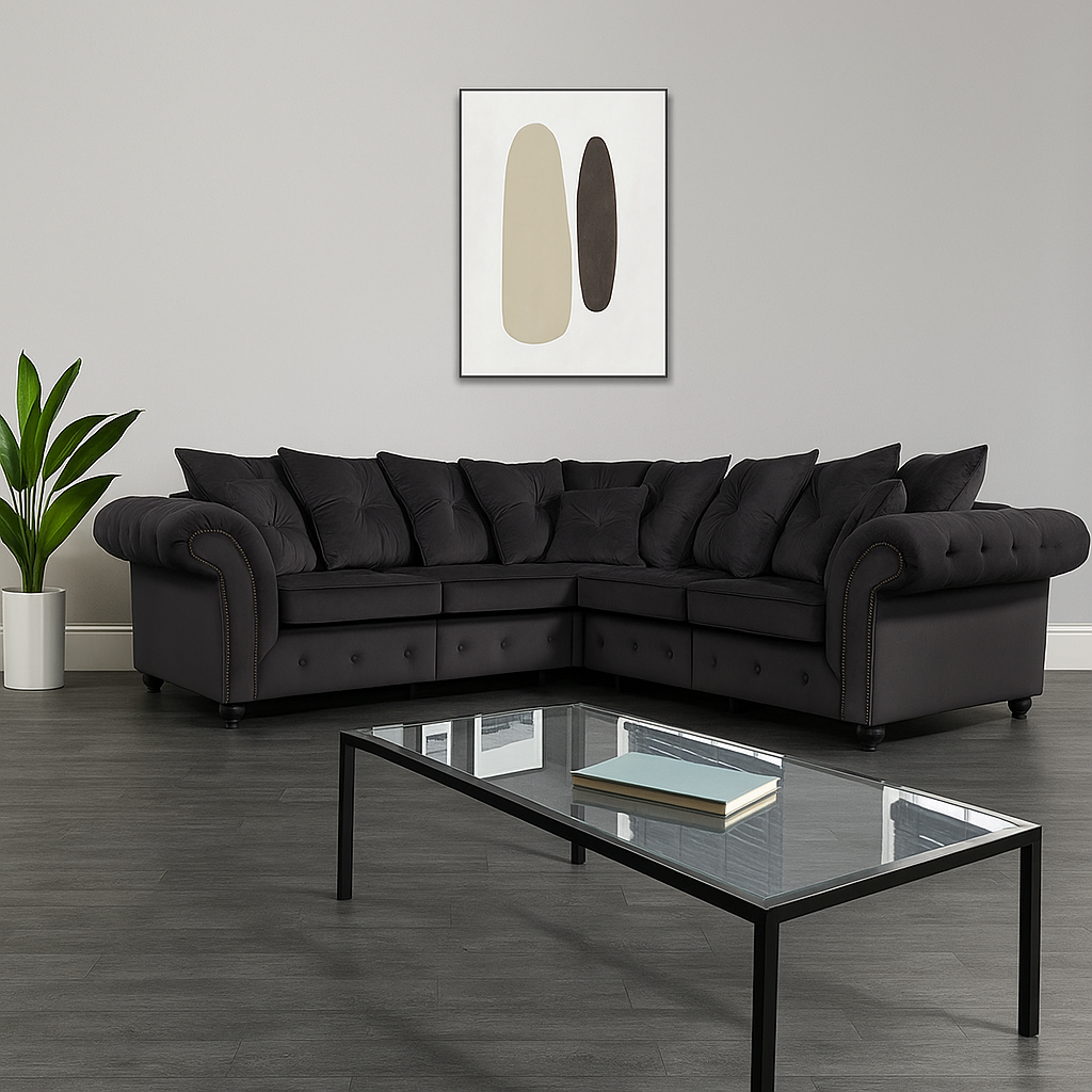 Modern living room with a black sectional sofa, glass coffee table, and abstract art on the wall.