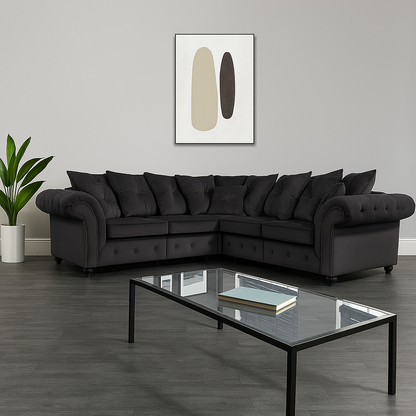 Modern living room with a black sectional sofa, glass coffee table, and abstract art on the wall.