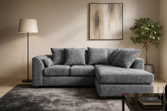 Gray sectional sofa in a living room with a lamp, plant, and abstract painting.